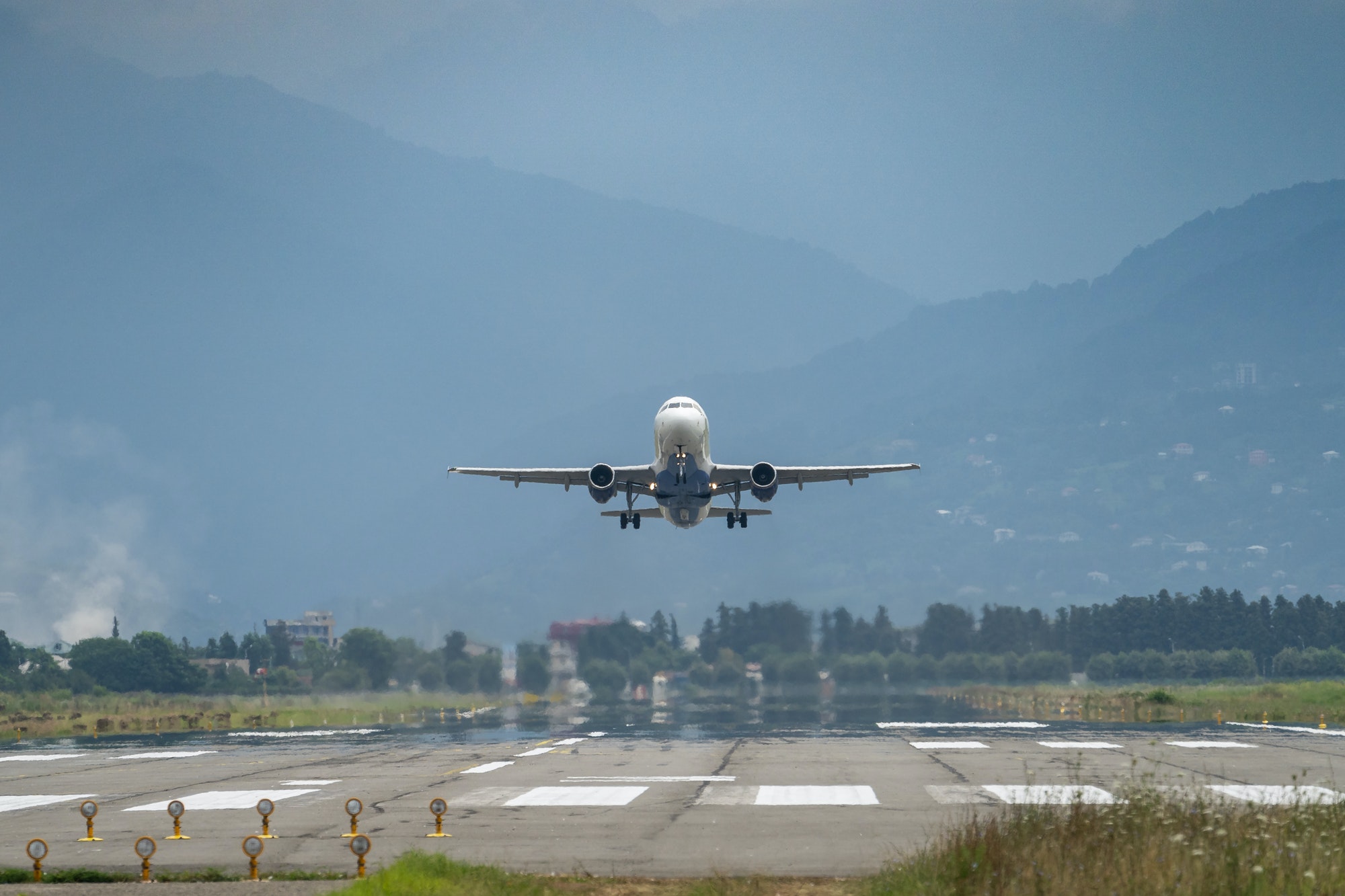 Airplane taking off from the airport, mountains on background. Transportation concept