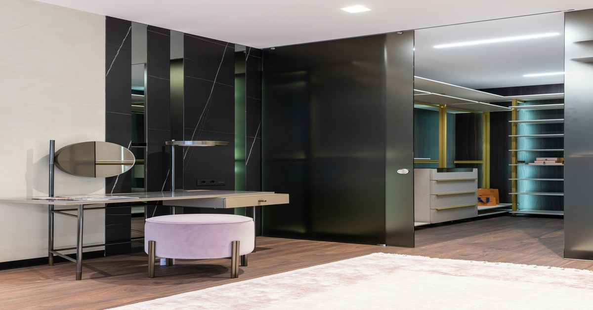 Elegant art deco walk-in closet featuring black lacquer cabinets, polished brass handles, and a geometric patterned rug