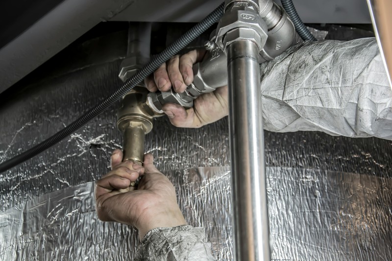 DIYer assembling an industrial pipe closet system using a pipe wrench and level on the floor