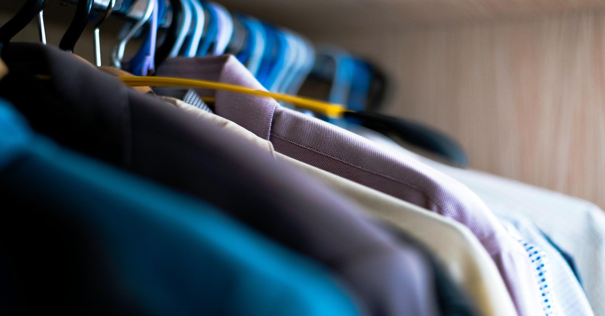 A selection of different clothes hangers including wood, velvet, and plastic styles arranged on a closet rod