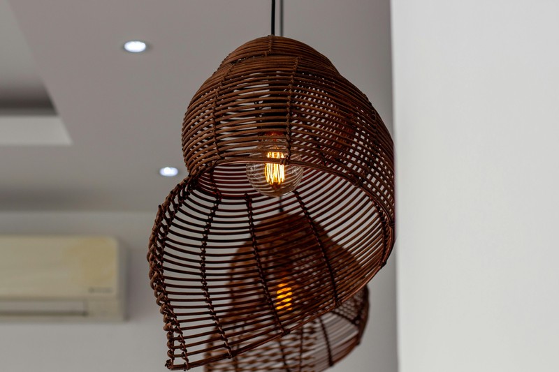 Layer lighting in a boho closet with a rattan pendant light and warm fairy lights